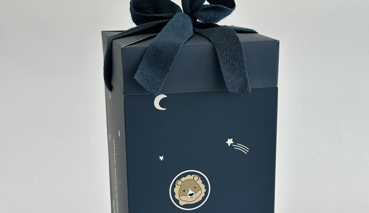 Dunkelblaue Geschenkbox von Rock my Sleep mit Stoffschleife, auf der Vorderseite ein Löwe, Sterne und ein Mond