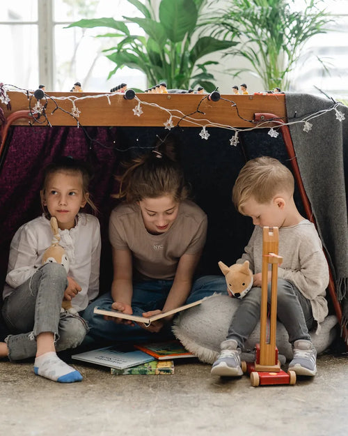Drei Kinder lesen in einer Deckenhöhle, Ivy und Peter sitzen dabei.