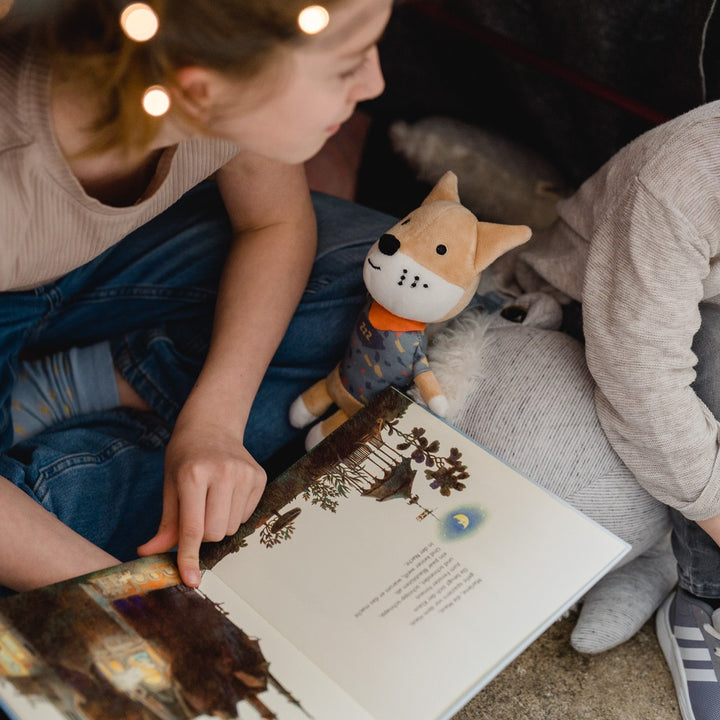Kinder schauen zusammen ein Buch an, die Spieluhr Peter der Fuchs sitzt mittendrin